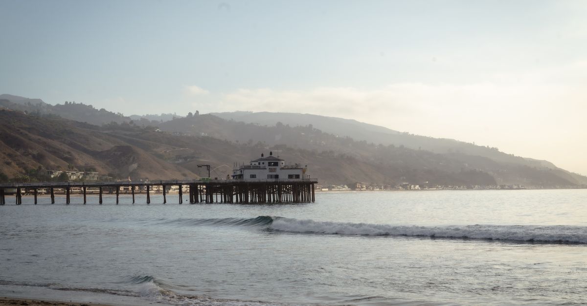 Tranquil morning view of Malibu Pier extending into the ocean with a mountainous backdrop.