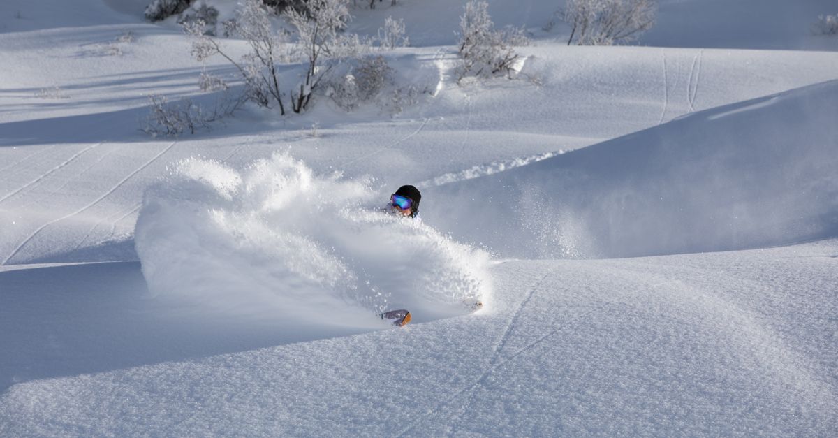 A skier navigates through deep powder snow in Gaschurn, Austria, showcasing dynamic winter sports action.