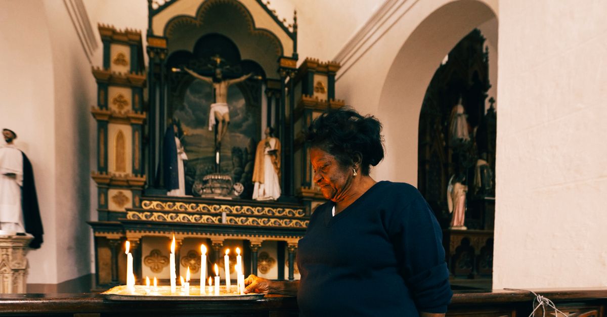 An adult woman lights candles at a church altar, embracing spirituality and reflection.