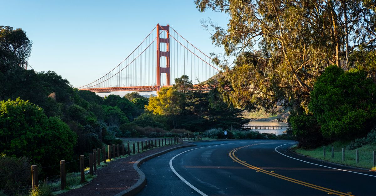 A scenic road with a view of San Francisco's iconic Golden Gate Bridge at daylight.