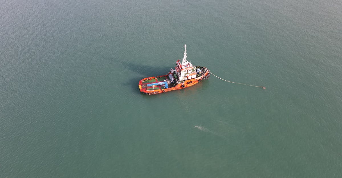 Aerial view of a red tugboat navigating the calm waters in Port Dickson, Malaysia.