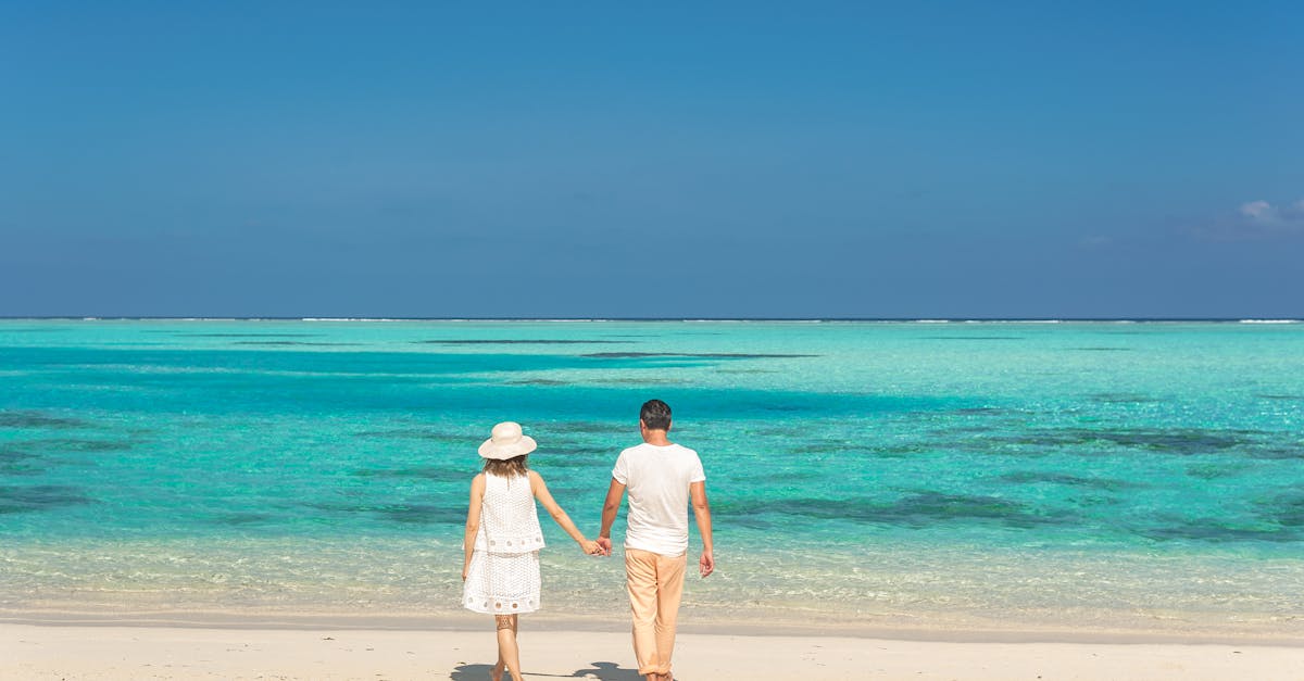 Couple walking hand in hand on a sunny beach, enjoying a romantic seashore getaway.