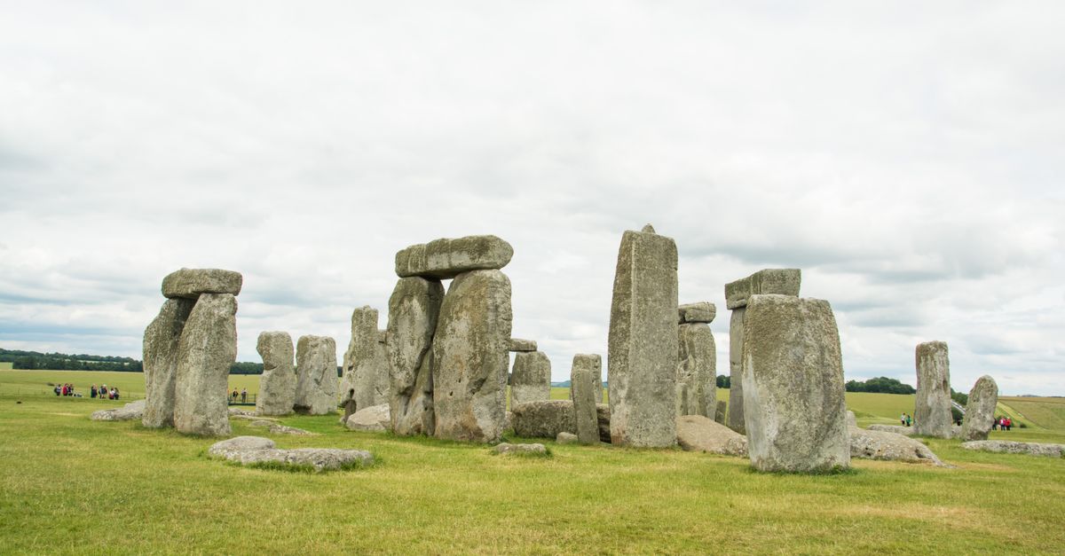 View of Stonehenge against a cloudy sky with green grass surroundings.