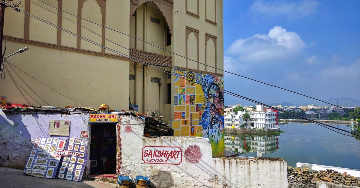 Vibrant Sakshi Art School entrance with mural by Udaipur lake on a sunny day.