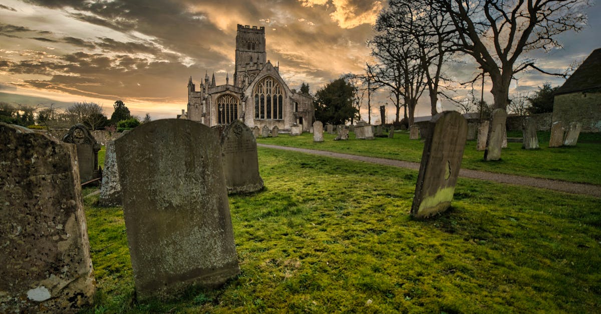 A tranquil cemetery with old tombstones and a gothic church during a vibrant sunset.