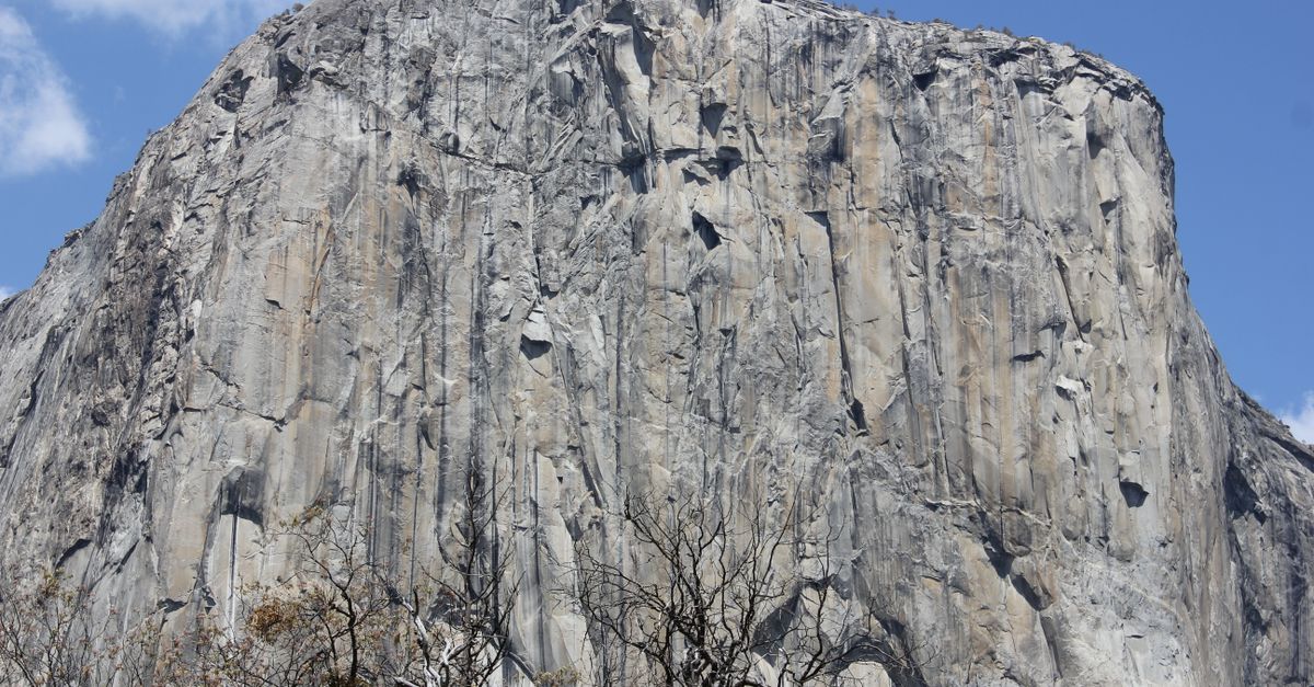 Stunning view of El Capitan rock formation under a clear blue sky, Yosemite National Park.