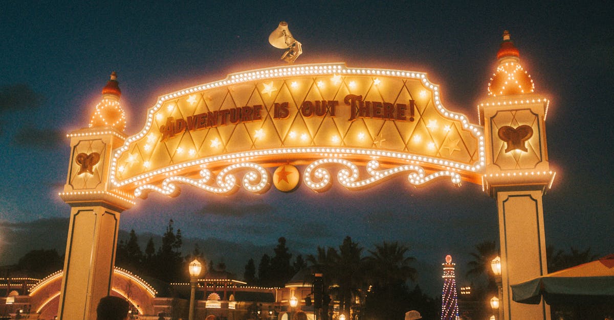 Entrance sign at a lively theme park, glowing with lights during night time.