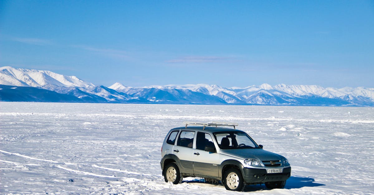 An SUV parked on a snowy expanse with majestic mountains in the background, capturing the essence of winter travel.