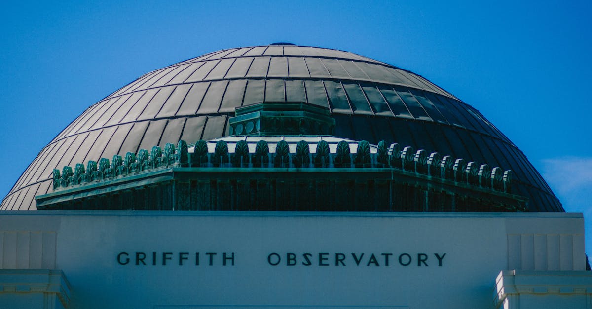 Close-up of Griffith Observatory's dome with 'Griffith Observatory' text under a clear blue sky.