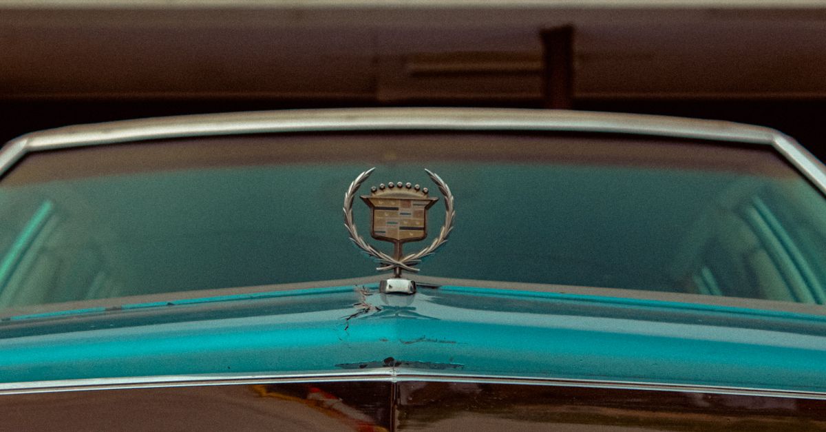 Close-up of a vintage Cadillac hood featuring its classic emblem, epitomizing nostalgia and luxury.