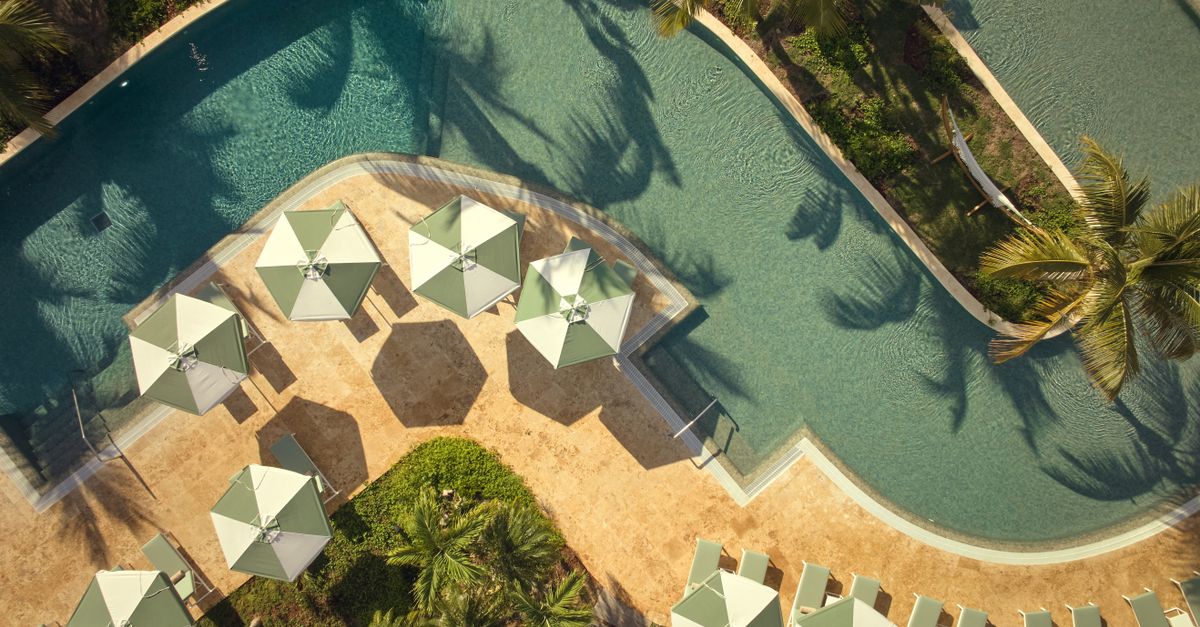 Aerial shot of a resort pool with umbrellas and palm trees in Samana, Dominican Republic.