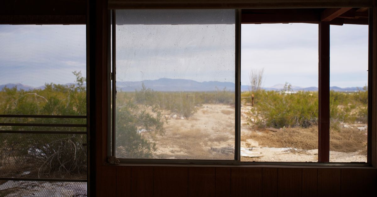 Desolate view through a window of an abandoned house in the arid desert landscape.