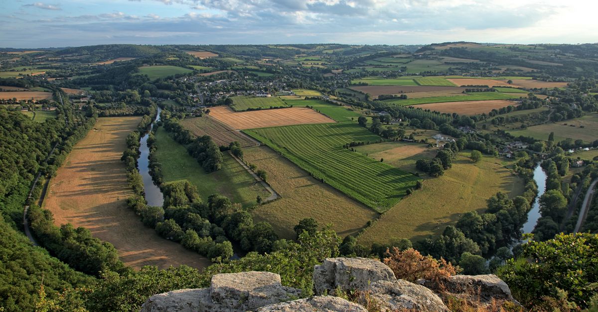 Breathtaking aerial view of the rural landscape in Clécy, Normandy, France with lush fields and winding rivers.