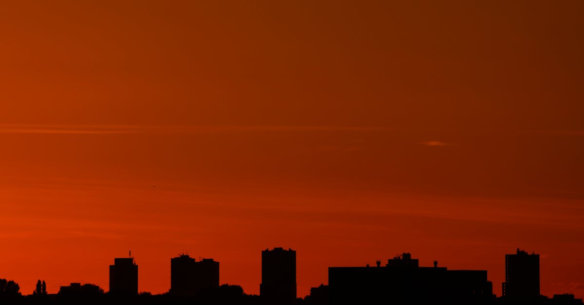 Silhouette of skyscrapers against a vibrant sunset sky in an urban landscape.