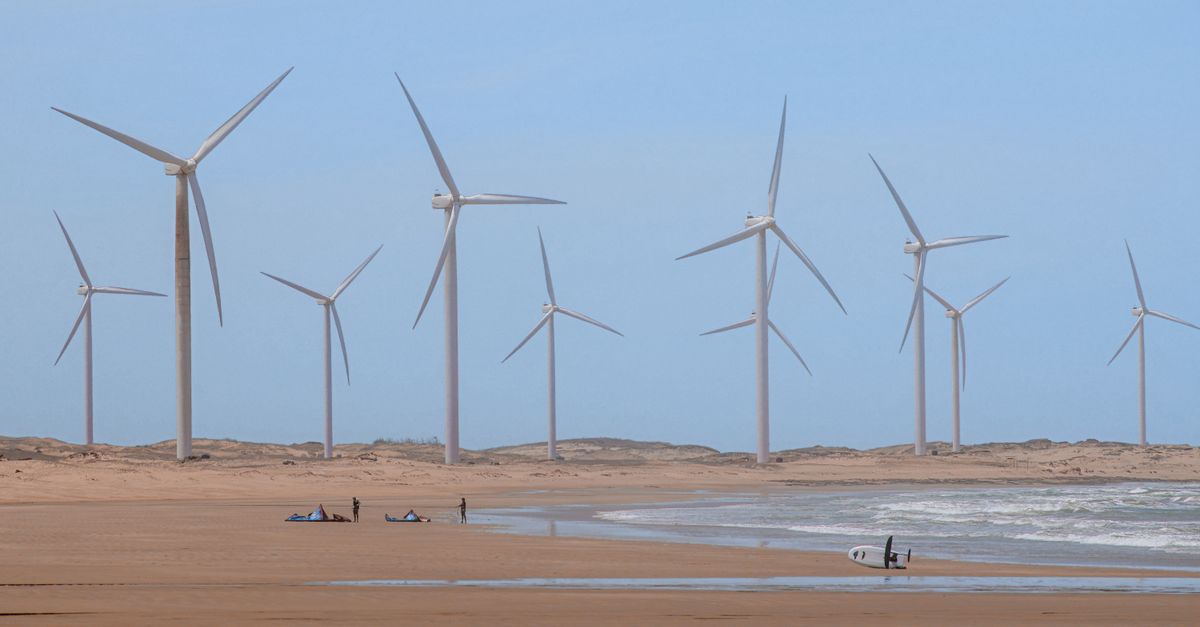 Scenic wind turbines at Icaraí beach, Ceará, Brazil with surfers nearby.