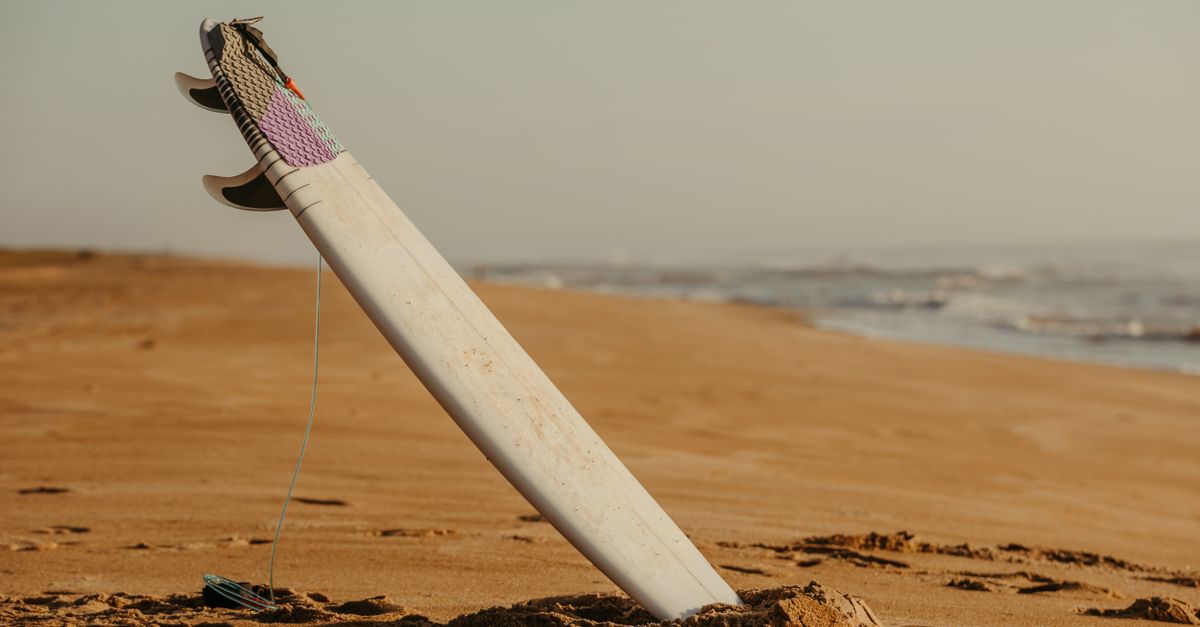 Surfboard standing in sand on a deserted beach, perfect for water sports imagery.