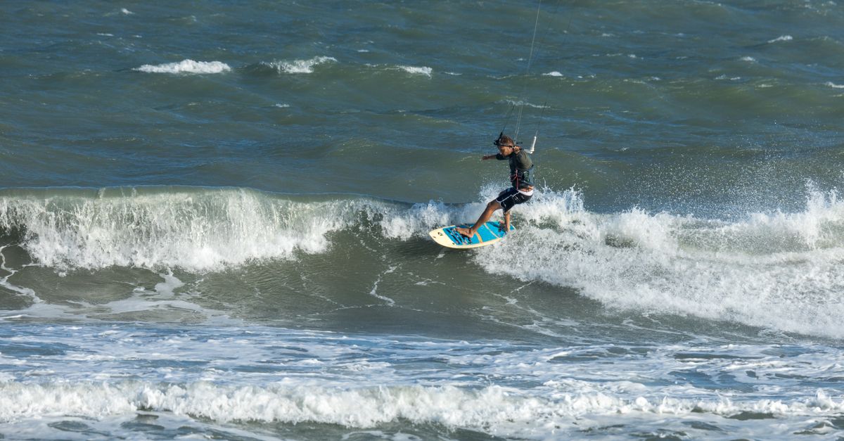 Man skillfully kitesurfing on rough ocean waves, capturing the thrill of adventure and water sports.