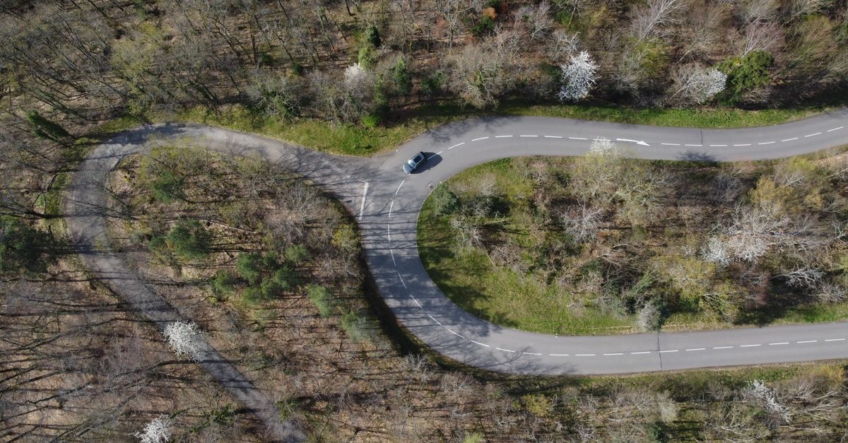 Drone shot capturing a curvy road through a forest in Kintzheim, Grand Est, France.