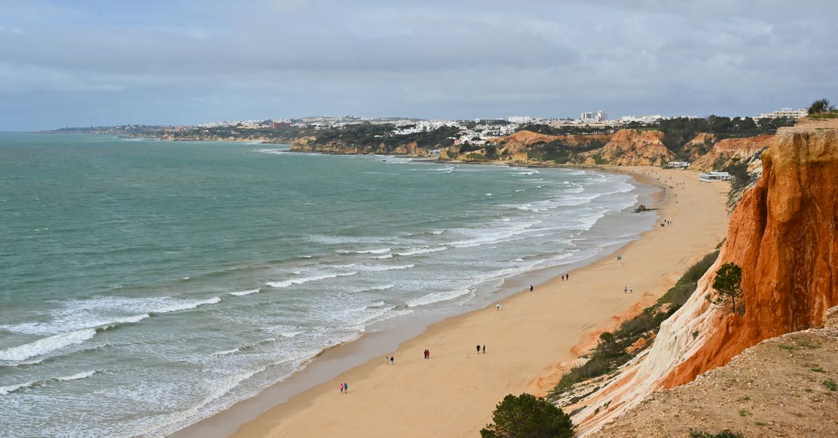 Beautiful aerial view of Albufeira's coastline with unique red cliffs and azure sea waves.