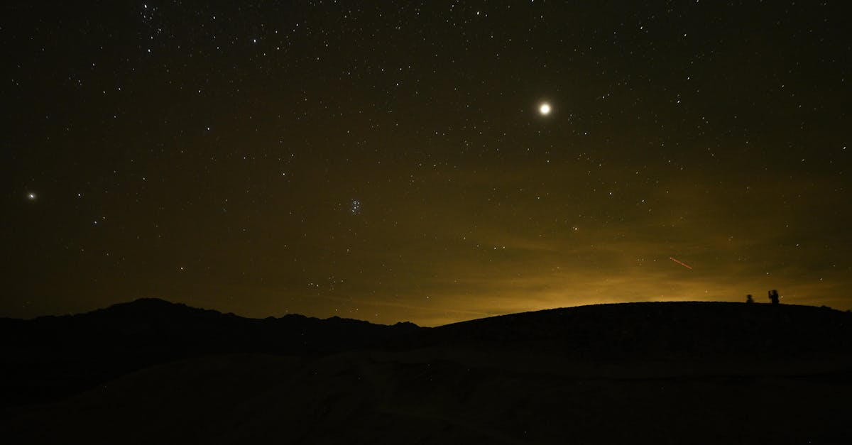 Starry sky with bright moon above landscape silhouette in Death Valley, California.