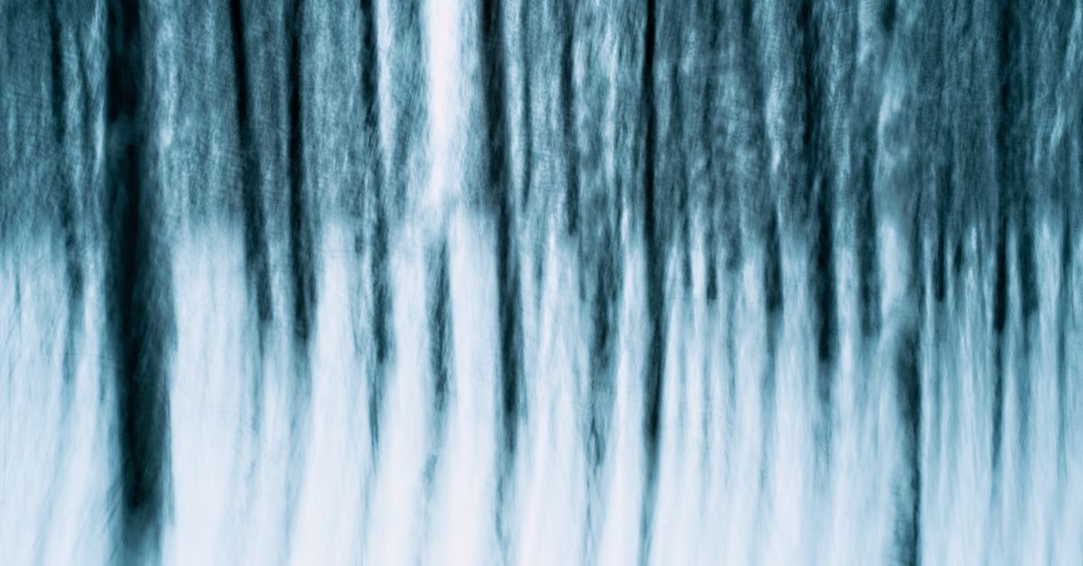 Dreamlike abstraction of a winter forest with blurred vertical tree patterns.