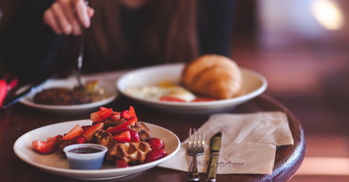 Enjoy a delicious brunch featuring waffles topped with fresh strawberries and a side of jam.
