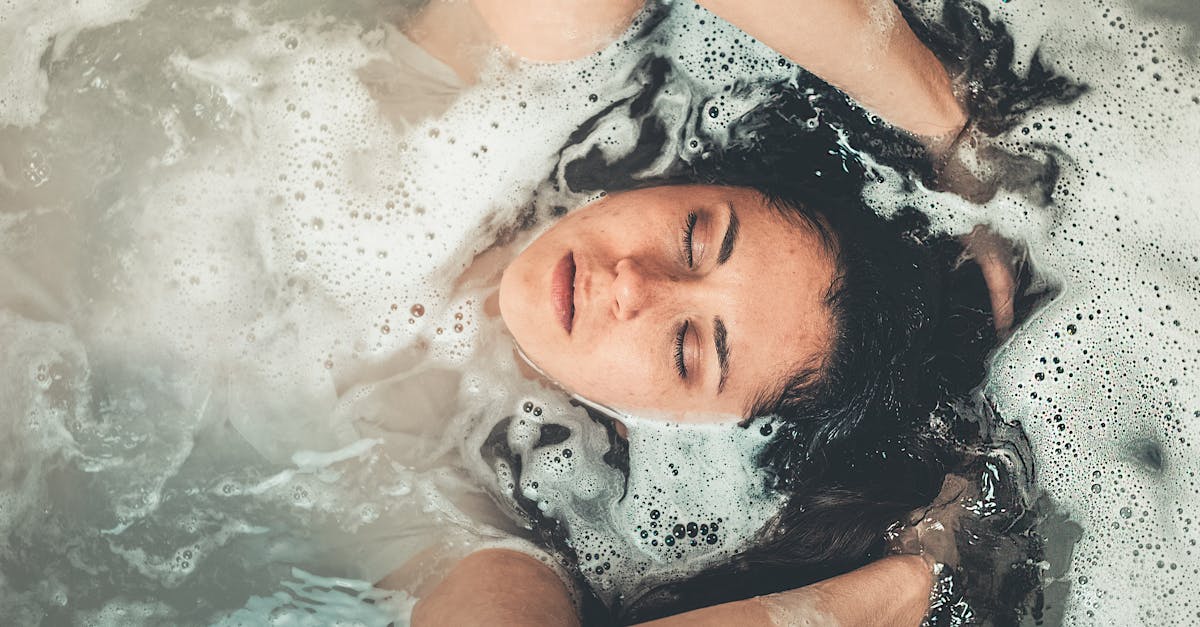 Calm and serene young woman enjoying a bubble bath with her eyes closed.