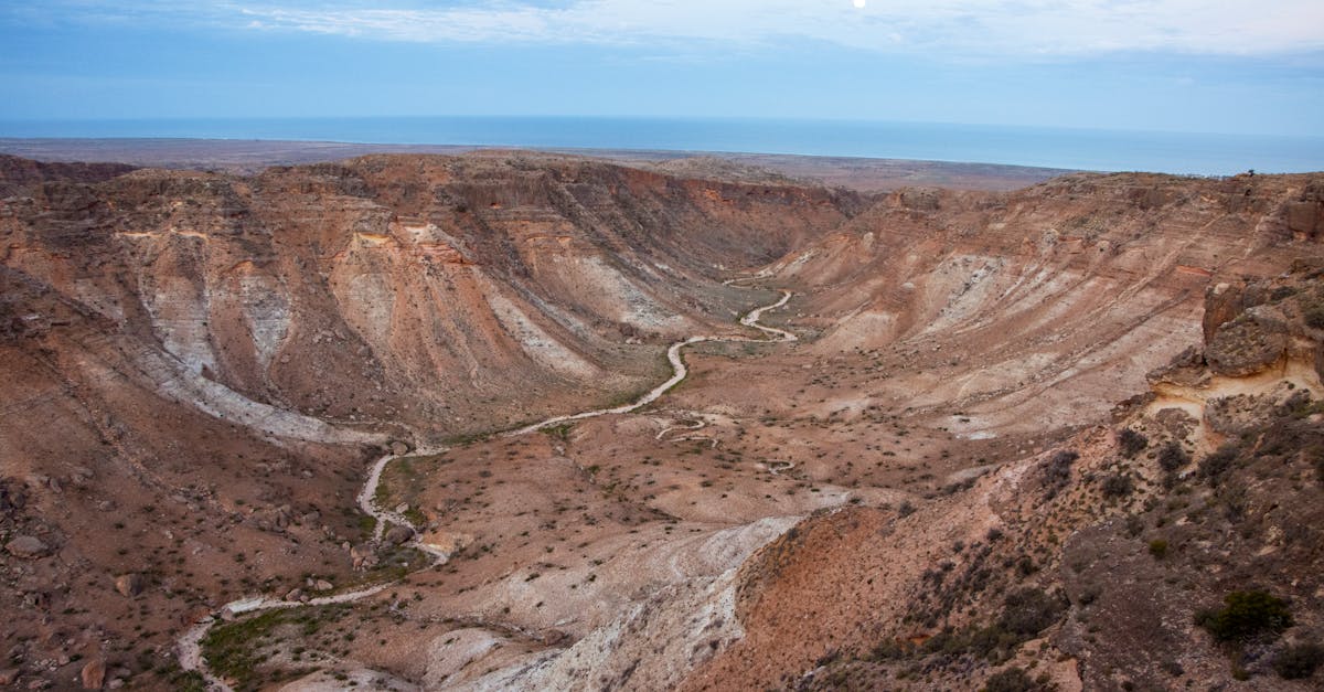 Wide view of Exmouth canyons at dusk with moonrise and geological formations.