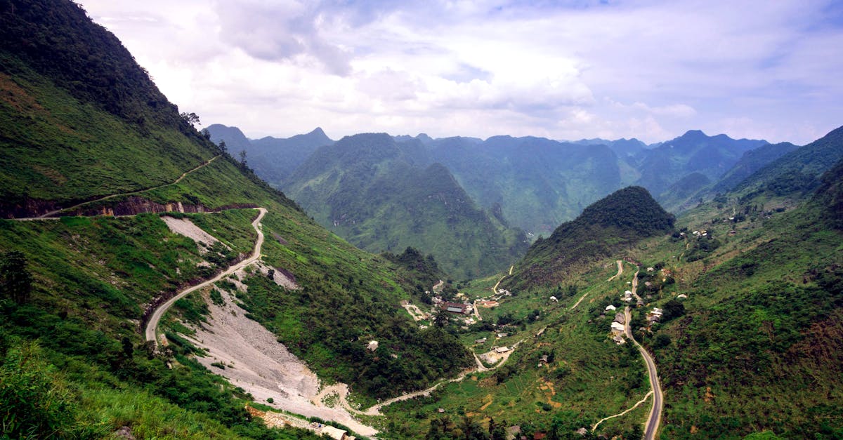 A breathtaking aerial view of winding roads traversing lush green hills and valleys under a clear sky.