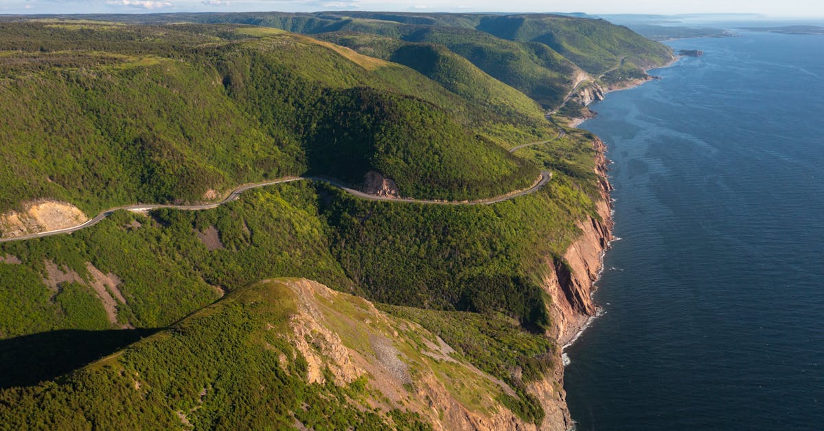 Explore the breathtaking cliffs and coastline of Cape Breton Highlands, showcasing lush green hills and rugged ocean views.