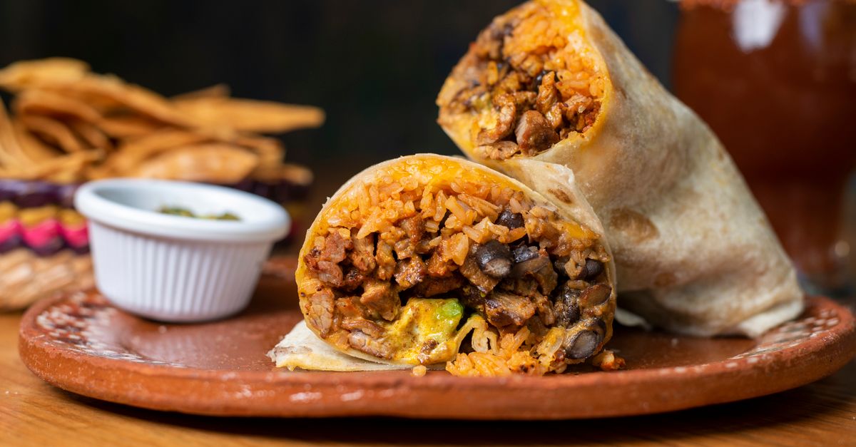 Mouthwatering beef and rice burrito served on a rustic plate with chips.