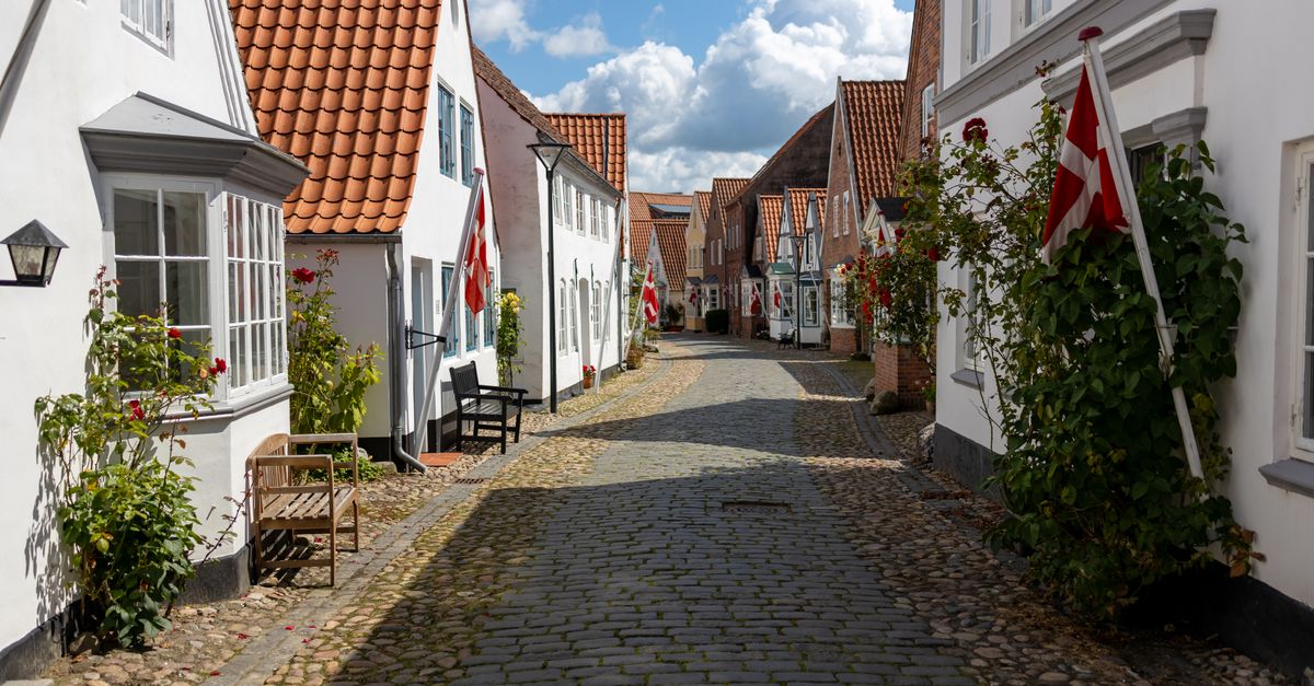 Picturesque cobblestone street lined with quaint homes and Danish flags in Tonder, Denmark.