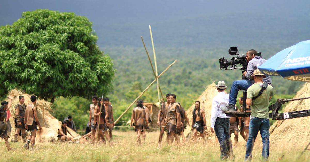 Behind the scenes view of a film crew capturing a scene on an outdoor set with actors and natural scenery.