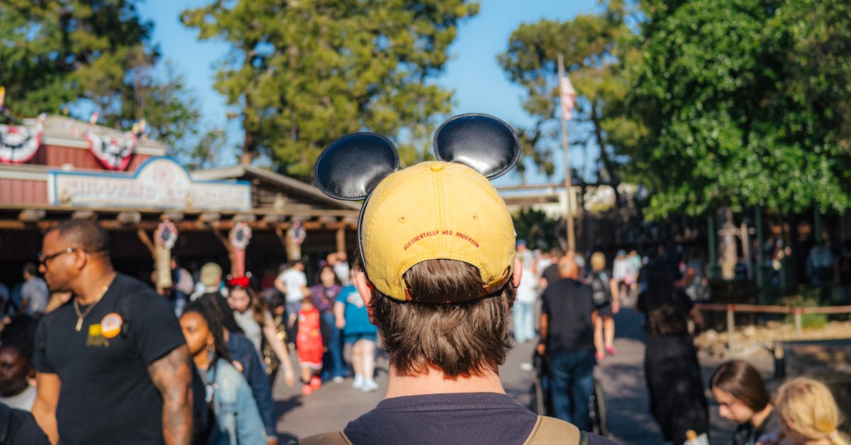 Visitor wearing Mickey ears explores a sunny Disneyland park in Anaheim, California.