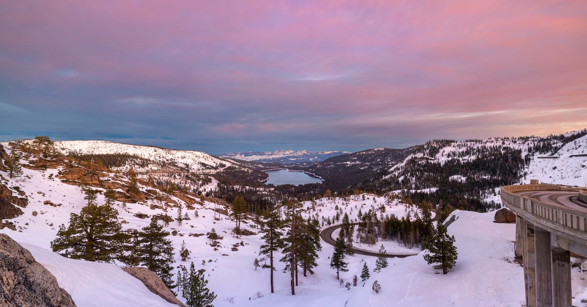 Stunning sunset view of snowy Donner Lake and mountains, capturing nature's serene winter beauty.