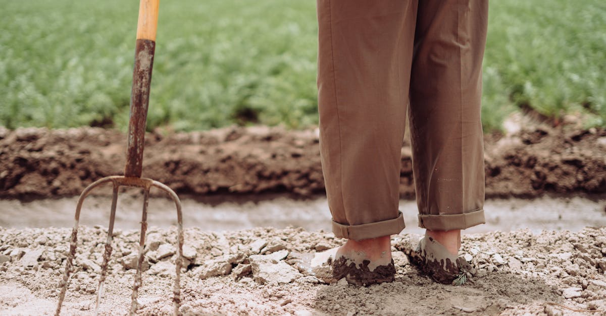 Man standing in muddy farm field with pitchfork in Mendoza, Argentina.