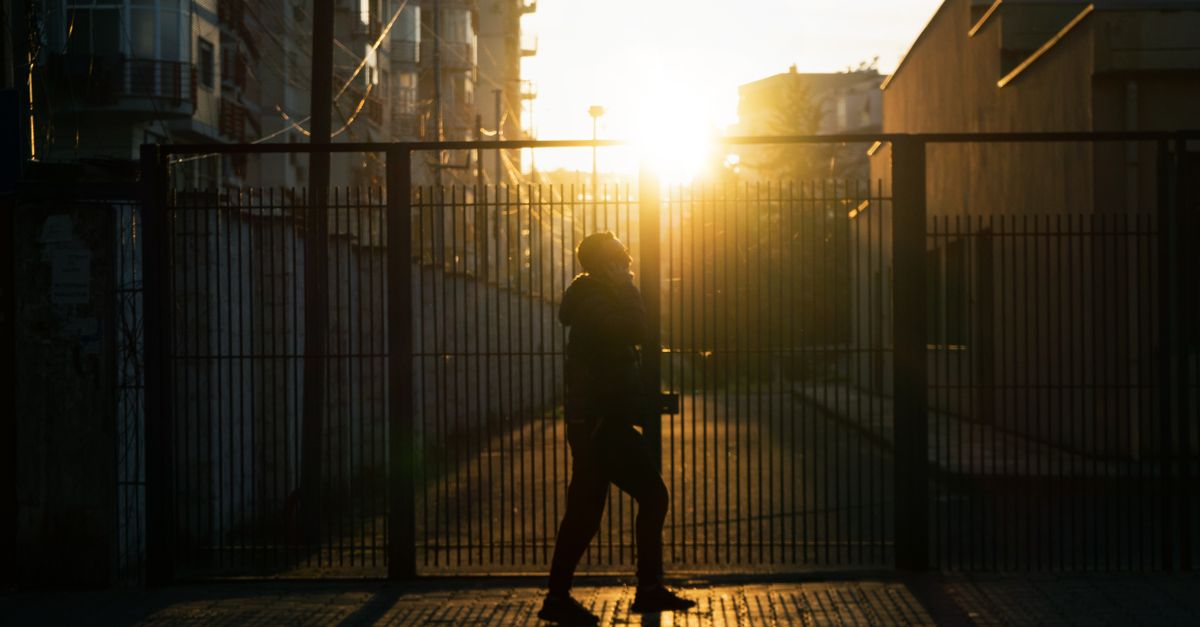 Silhouette of a person walking by a gate during sunset in Tirana, Albania.