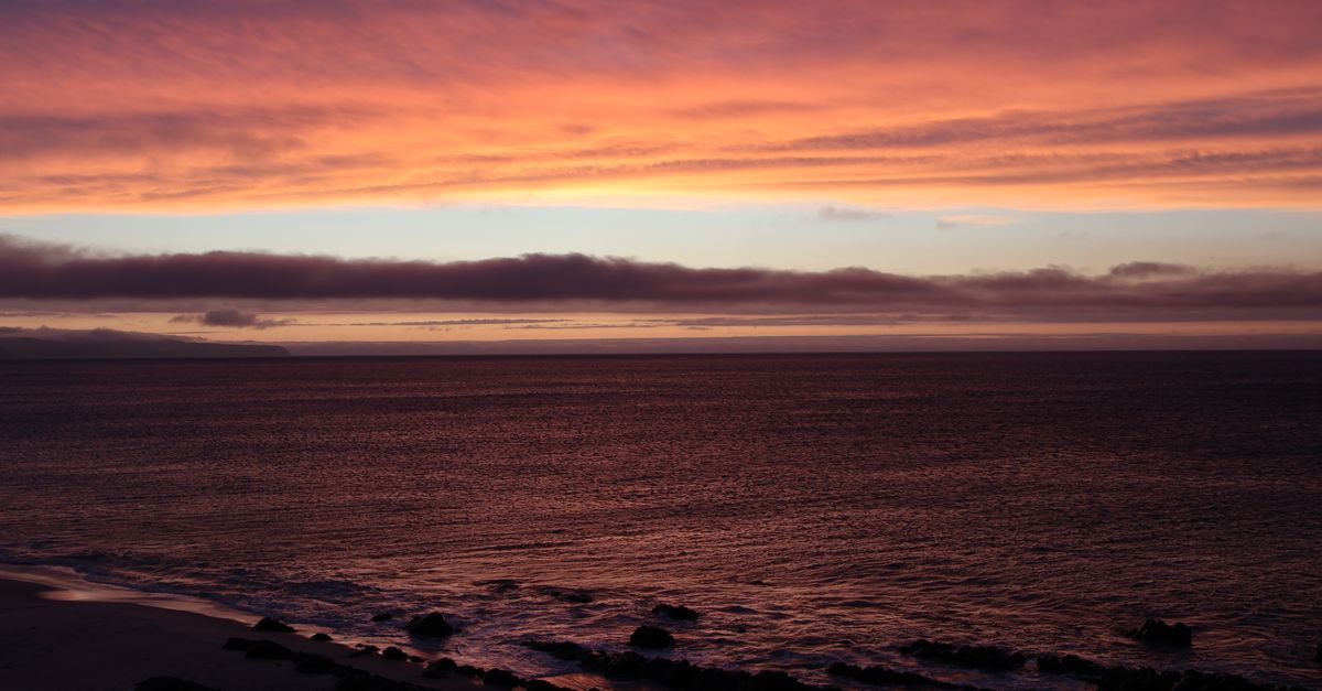 A serene ocean view at sunset with vibrant, colorful skies and gentle waves.