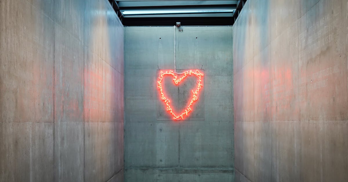 A glowing neon heart installation in a sleek concrete hallway.