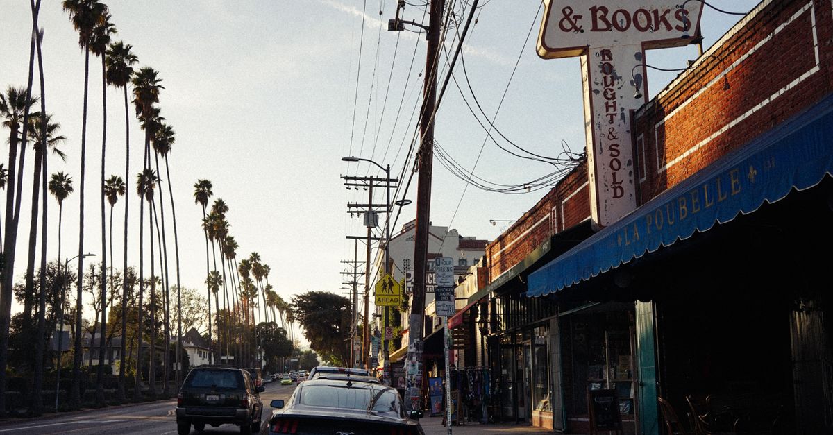 Charming street view at sunset with palm trees and a vintage bookstore in an urban setting.