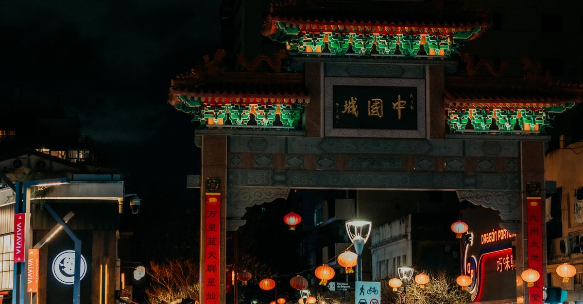 Vibrant night scene of a beautifully lit traditional Chinese archway in a bustling city Chinatown.