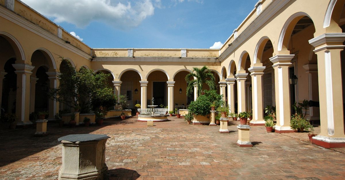 Scenic view of a colonial courtyard with arches and plants, showcasing historic Cuban architecture.