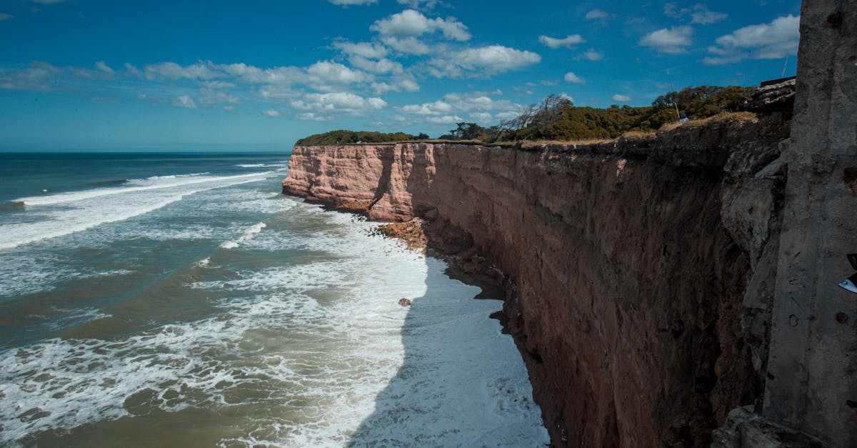 Majestic ocean view with stunning cliffs under a bright blue sky, showcasing nature's beauty.