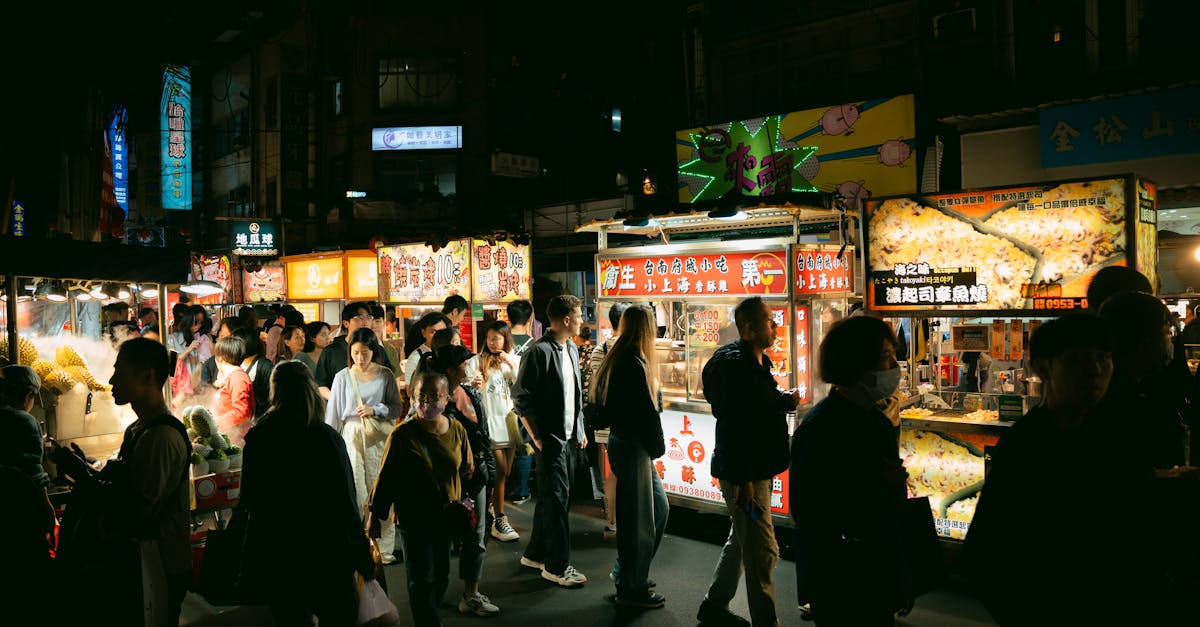 Crowded night market with food stalls offering a variety of dishes and a lively atmosphere.