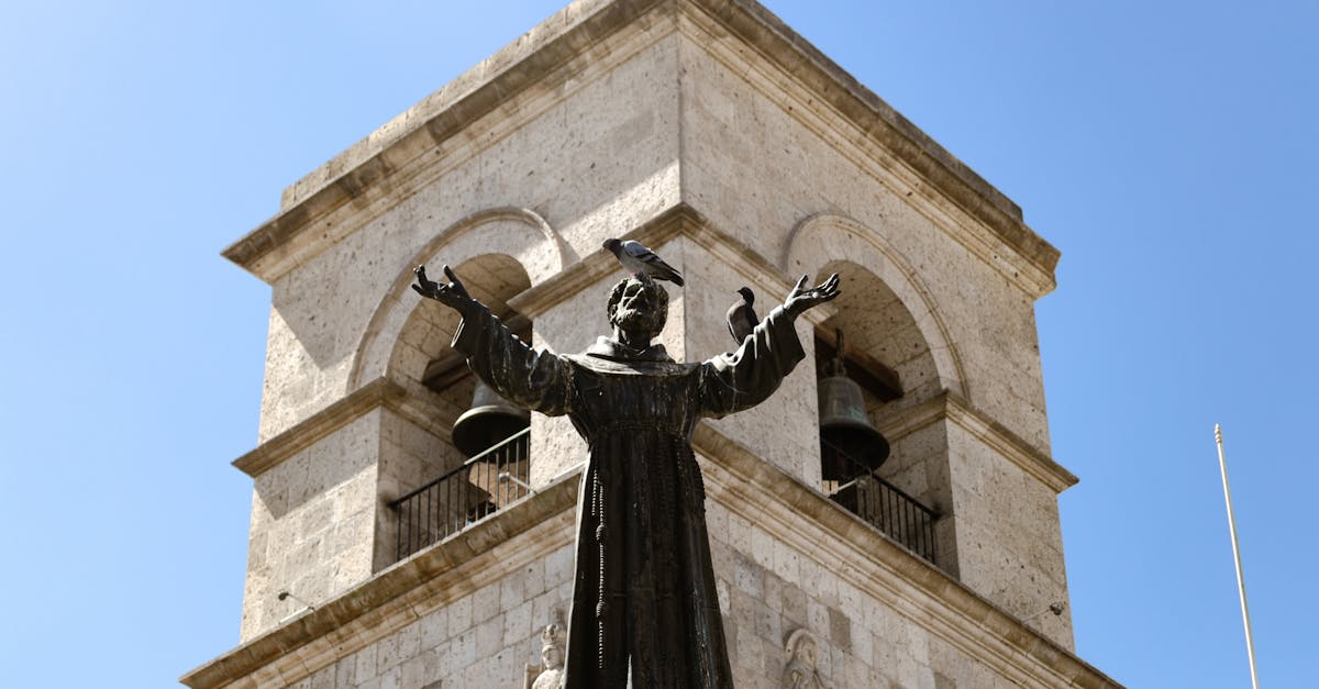 View of a church tower and religious statue under a blue sky in Arequipa, Peru.