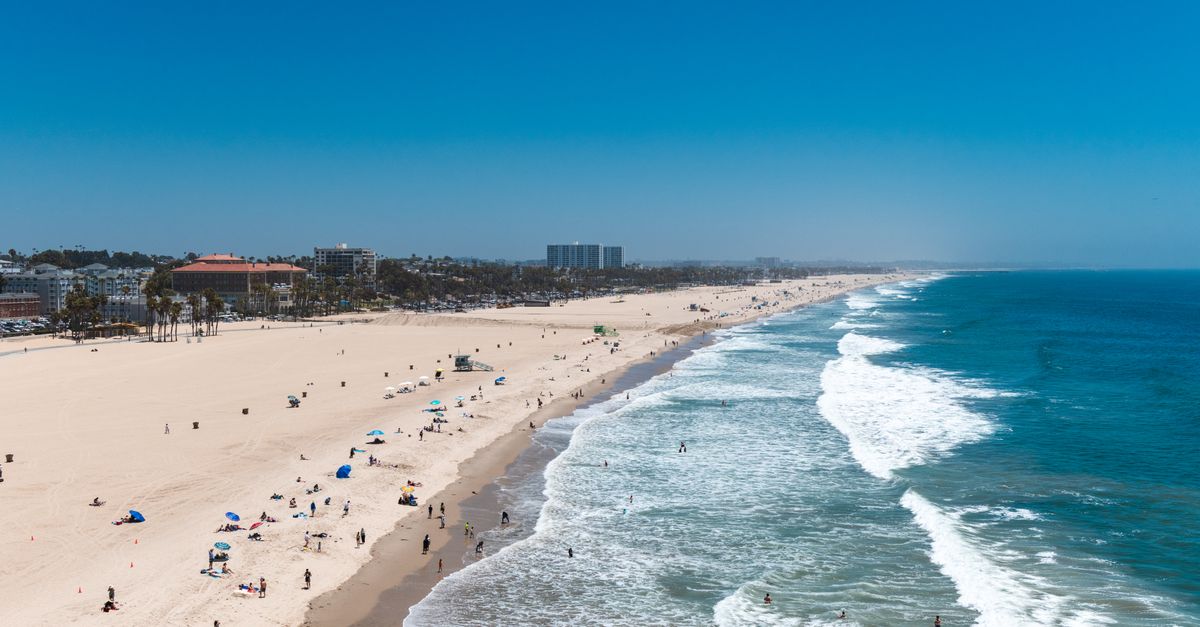Aerial view of a lively beach scene at Santa Monica, capturing people enjoying the sun and sea.