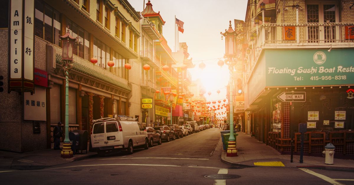Chinatown street view at sunset with traditional lanterns and urban architecture.