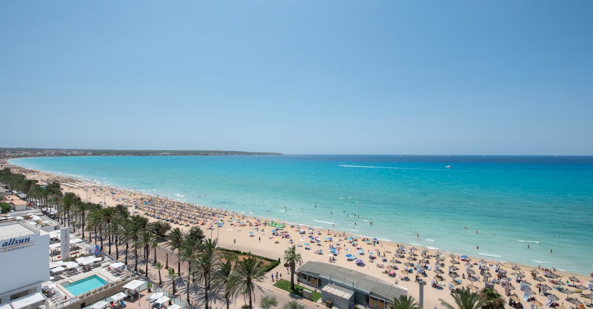 Aerial view of a vibrant beach in Palma with turquoise waters and tourists enjoying a sunny day.