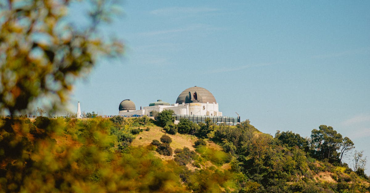 Scenic view of Griffith Observatory surrounded by lush greenery under a clear sky.