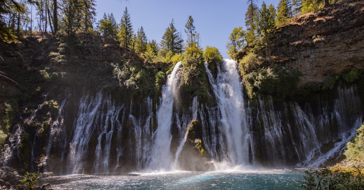 Majestic view of Burney Falls with lush greenery and clear blue water, captured during a sunny day.